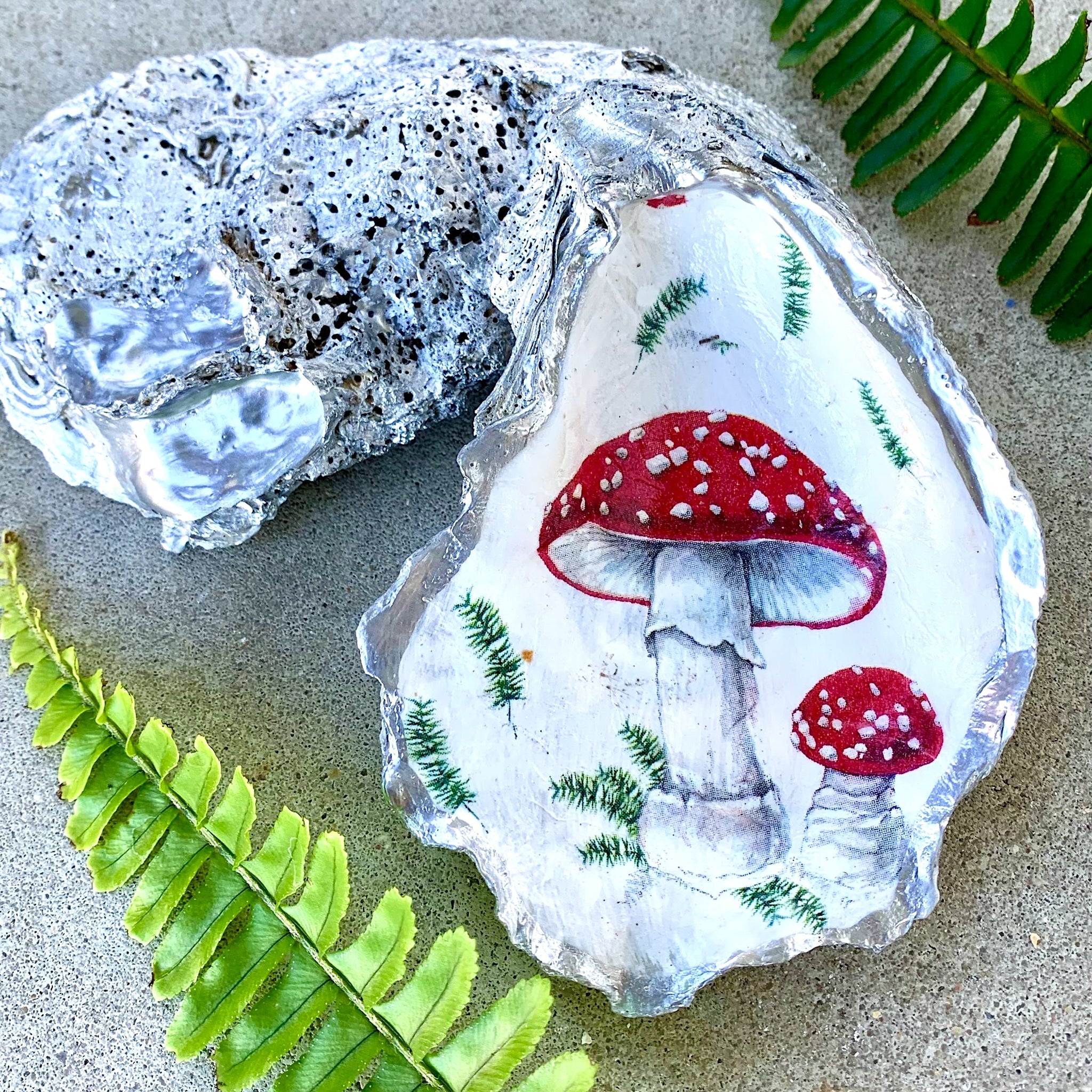 red mushroom image decoupaged onto a large recylced oyster shell, trimmed  and painted on the back in metallic silver paint